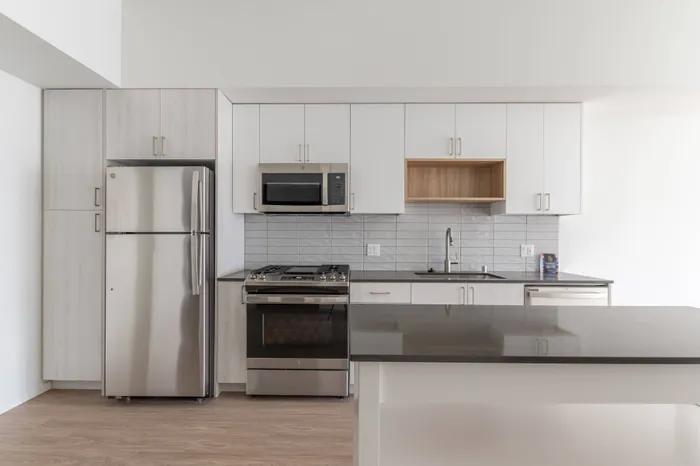 Elegant kitchen with storage nook above sink and light kitchen cabinets with large island in an apartment at Modera River Trail.
