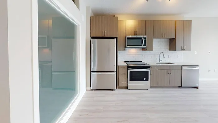 Galley style kitchen, plank-style flooring, and bedroom privacy walls at Modera Creative Village apartments