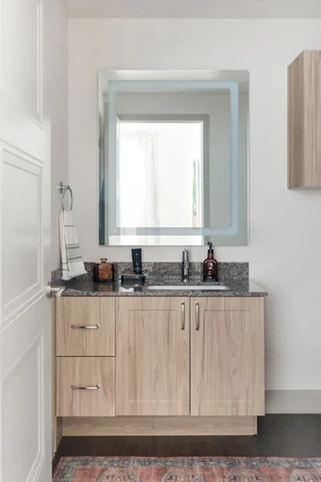 Choice of 2 Color Schemes: Dark or Light - bathroom vanity with oversized mirror at a Modera Six Pines apartment.