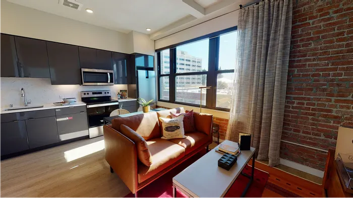 One bedroom  model home at Modera Berkeley with large windows and exposed brick wall.