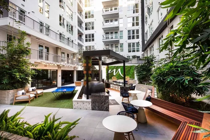 Full view of lounge space and outdoor kitchen in the courtyard under string lighting at Modera San Diego apartments.