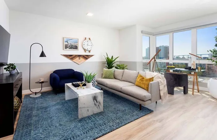 Large windows overlook views of the city and bay from a thoughtfully designed living room at a Modera San Diego apartment.