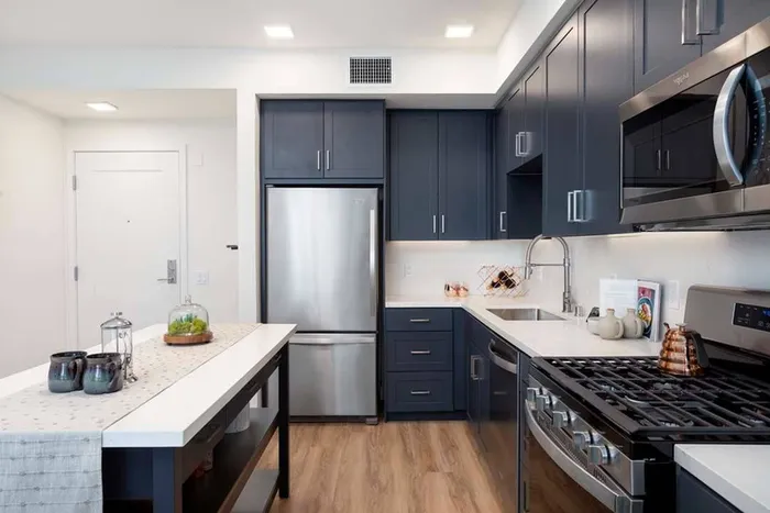 Kitchen at Modera San Diego with gas range, large kitchen island, pull-down faucet, single basin sink and shaker-style cabinets with modern hardware