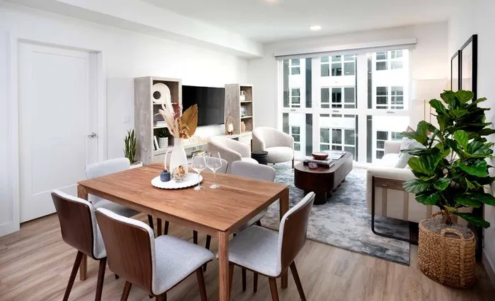 Living room with large windows, sofa and chairs and dining table at a Modera San Diego apartment.