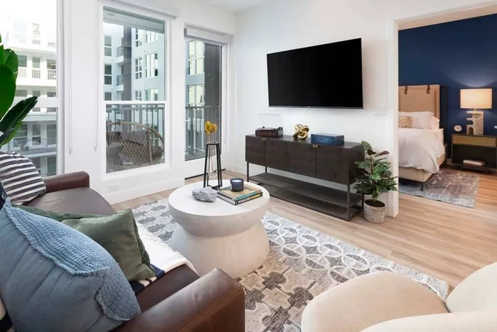 Balcony in the background along with bedroom entrance off of comfortable living room layout at Modera San Diego apartments.