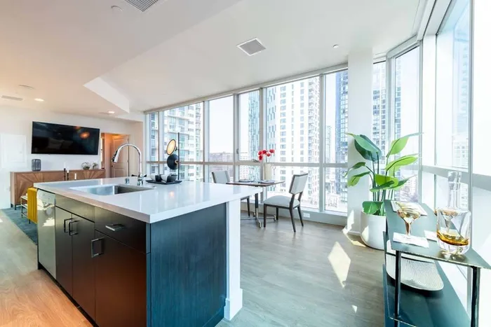 A large chef's island faces glass walls with the city beyond at Modera Rincon Hill apartments.