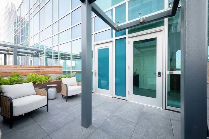 Rooftop patio with 2 chairs at penthouse home entrance under a glass overhang at Modera Rincon Hill apartments.