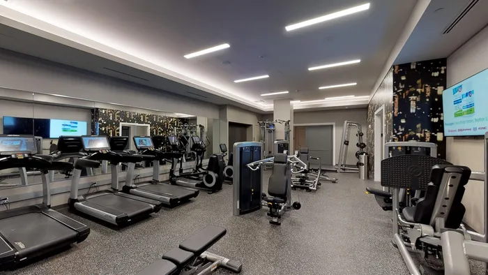 Club-quality fitness studio including cardio equipment with individual TV’s at Modera Needham Apartments.