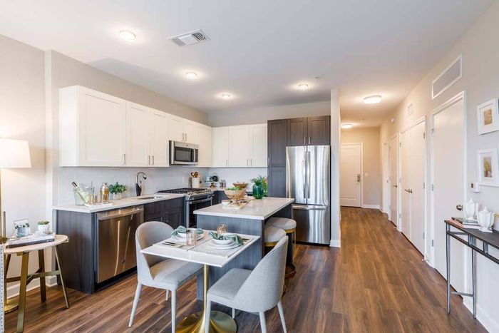 Light cabinets with kitchen islands and wood plank-style flooring