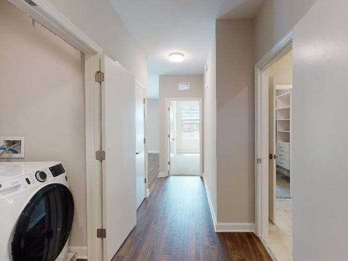 Entrance showing pass-through closet from bathroom into bedroom on the right, a bedroom ahead down the hall, and washer dryer on the left at the entry