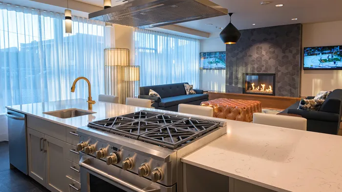 Demonstration kitchen featuring gas stove top and oven in Resident Lounge