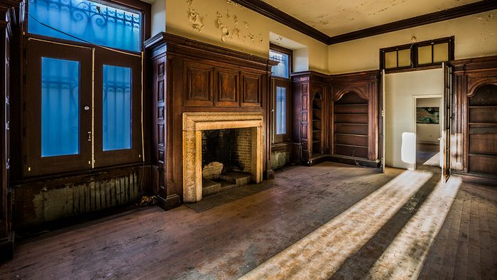 Cigar lounge with wood burning fireplace surrounded by wood panel walls and built in bookshelves