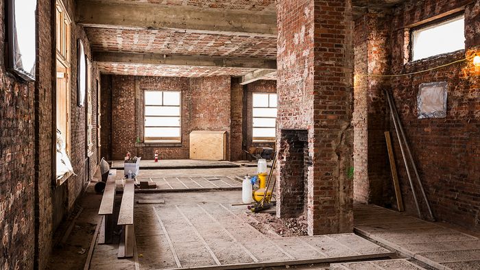 Well-lit room surrounded by windows and adorned in exposed brick during renovation