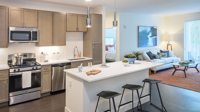 Modera Needham apartment kitchen features island & stainless steel appliances.