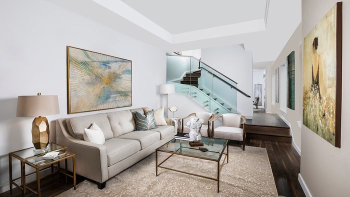 Living area with wood flooring throughout and glass staircase to second level