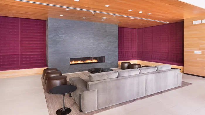 Resident lounge with velvet bench sitting reaching the ceiling along with large gas fireplace