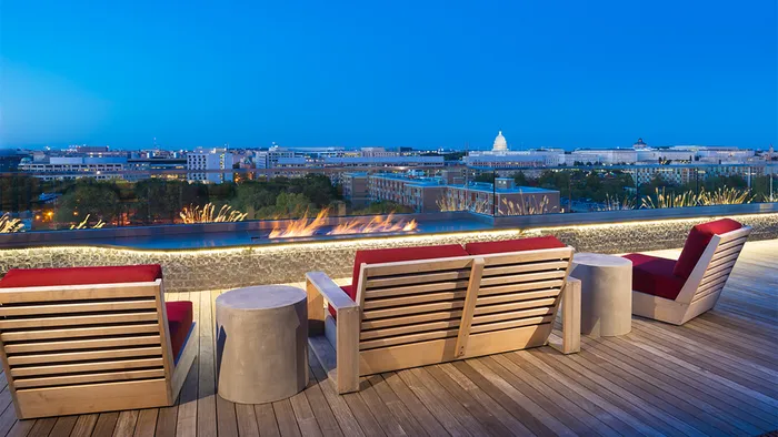Rooftop lounge with seating and fire pits overlooking the city