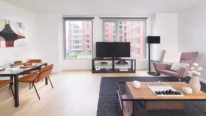 Living room with over sized windows with view of a desk and accent chair