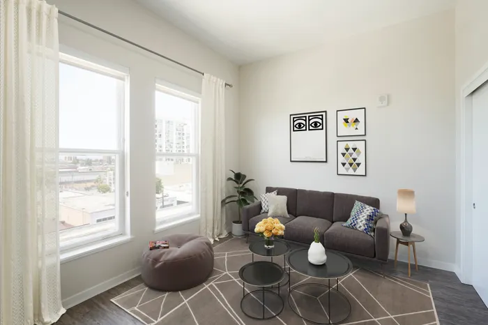 Light filled homes in Oakland, California with brown sofa a small brown poof chair and tall ceilings