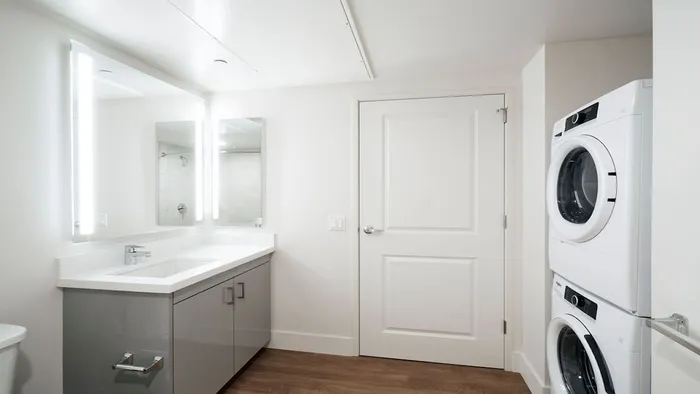 Bathroom with full-sized front loading washer dryer, backlit mirror and stunning vanities at Modera Rincon Hill apartments.