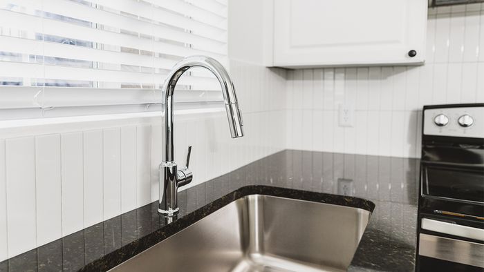 Close up on chrome kitchen spray nozzle with window above