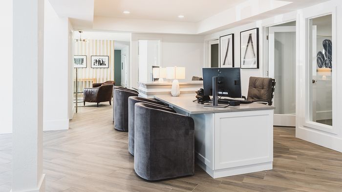 Brighty lit leasing office with desk and guest chairs