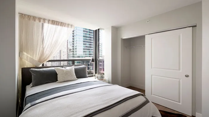 Large bedroom with sliding closets and built-in shelving at Modera Rincon Hill apartments.