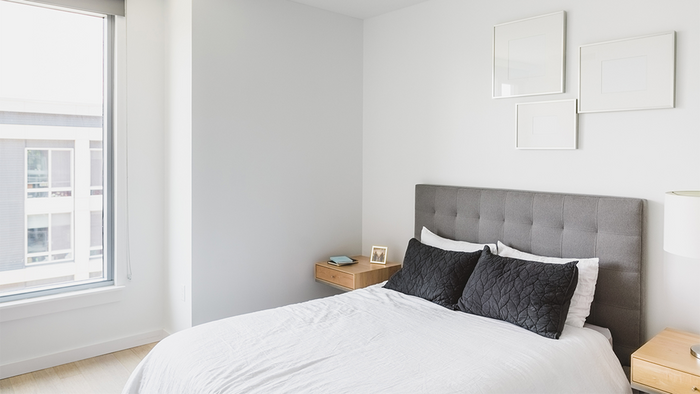 Bedroom with grey headboard bed and white sheets