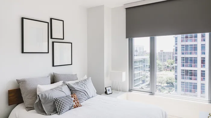 Bedroom with white bed, grey pillows and large window
