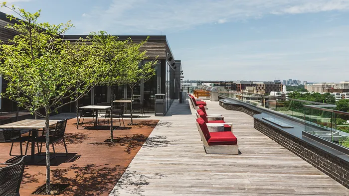 Outdoor roof lounge with red chaises and patio tables
