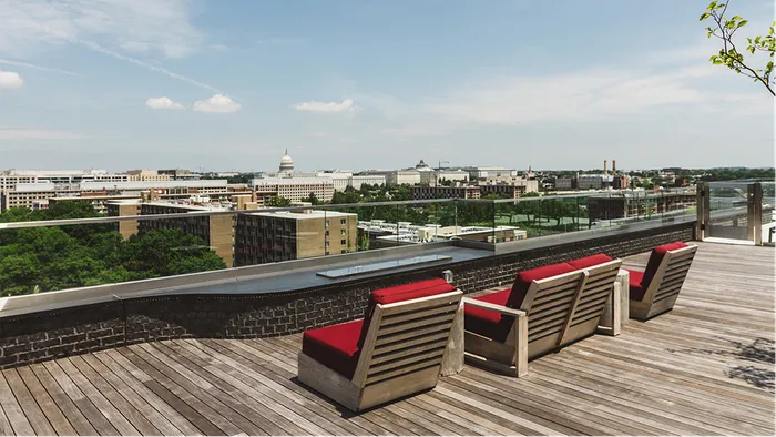Red chaise lounges over looking Washington, DC on rooftop deck