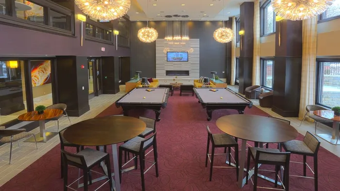 Resident lounge with unique light fixtures, billiards table, and ample seating