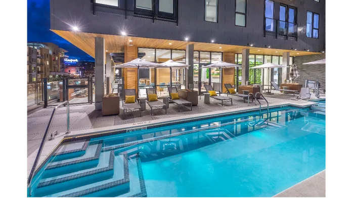 Elevated all-seasons resort-style pool, lounge seating, umbrellas, and a hot tub