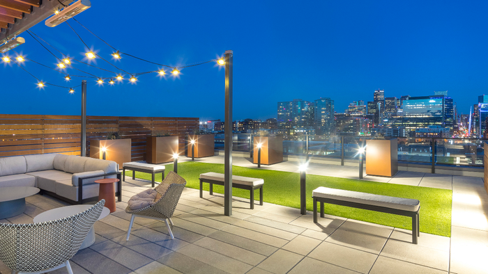 Private rooftop overlooking stunning city views with lounge seating under trendy lighting and outdoor heaters