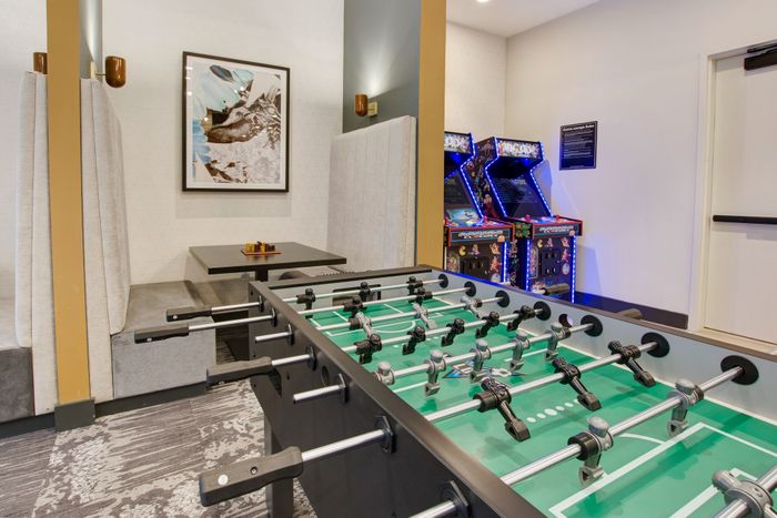 Resident lounge with game room featuring foosball, skee-ball, arcade games and shuffleboard at modera berkeley heights apartments in new jersey