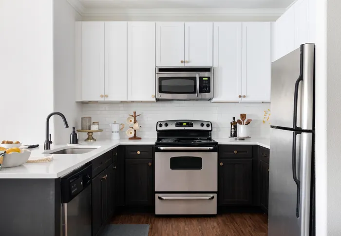 kitchen with two tone cabinetry and tile backsplash at alister oak hill apartments austin texas