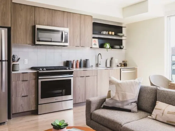 Galley-style kitchen in well-lit apartment home showing a stylish kitchen and living area at Modera Broadway Apartments.