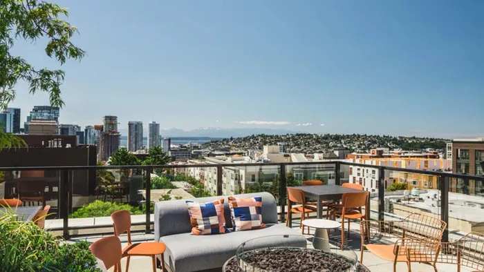 Lounge seating, firepit and dining table overlook Seattle and look towards the mountains at Modera Broadway apartments.