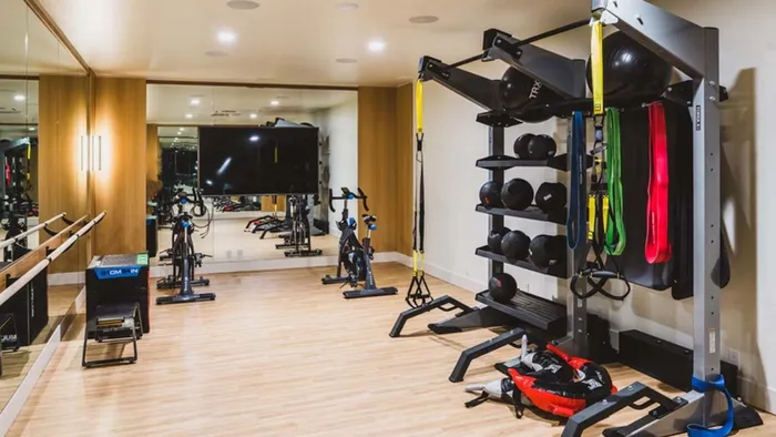 Yoga studio space with hardwood flooring, mirrors, ballet barre and TRX station at Modera Broadway apartments.