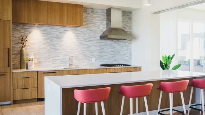 Demo kitchen with chef's island and barstool seating at Modera Broadway apartments.