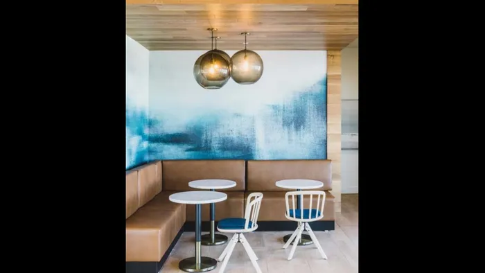 Banquet-seating nook with small tables and stylish lighting and artwork at Modera Broadway apartments.