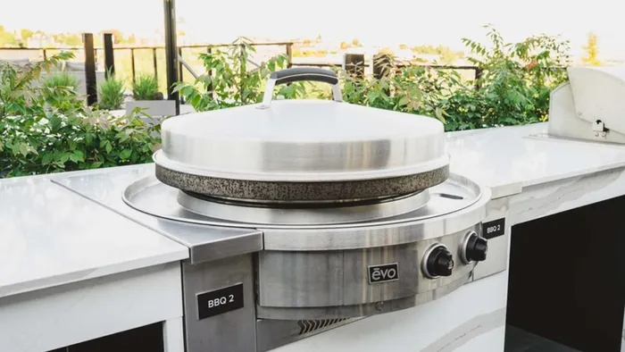 Closeup of EVO grill on rooftop with greenery in the background at Modera Broadway apartments.
