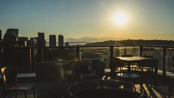 Rooftop deck lounge area with the sunset behind it over the mountains and the city at Modera Broadway apartments.
