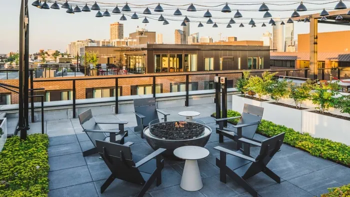 Rooftop fire pits and lounge seating under string lights at Modera Broadway Apartments.