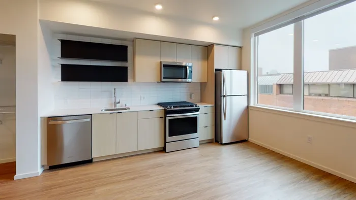 Galley Kitchen with view into living room in a Modera Broadway apartment.