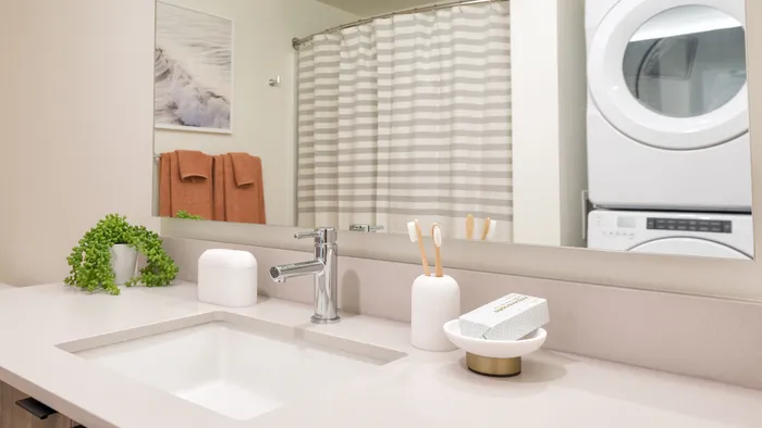 Bathroom with deep sinks, quartz countertops and full sized washer and dryer at Modera Broadway Apartments.