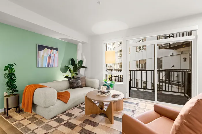 Living space with hardwood style flooring and private balcony in select units
