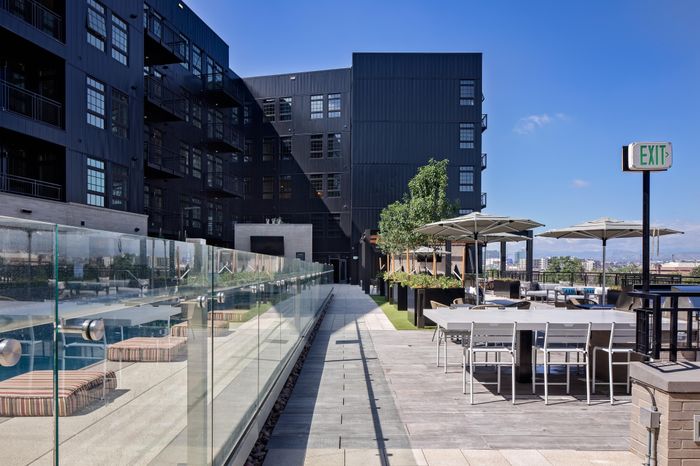 outdoor seating with umbrellas and green vegetation modera art park apartment homes for rent in denver colorado