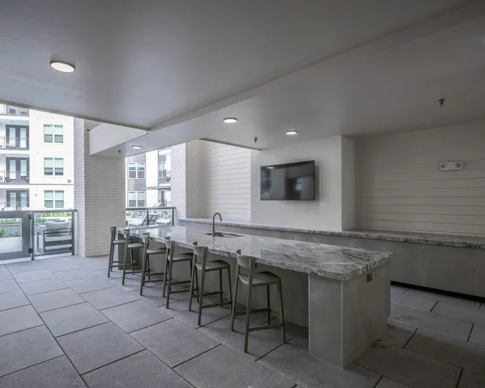 outdoor kitchen with island and seating at modera six pines apartment homes for rent in shenandoah texas