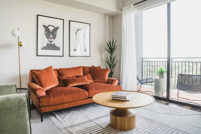 living room area overlooking city with large couch and hardwood style flooring